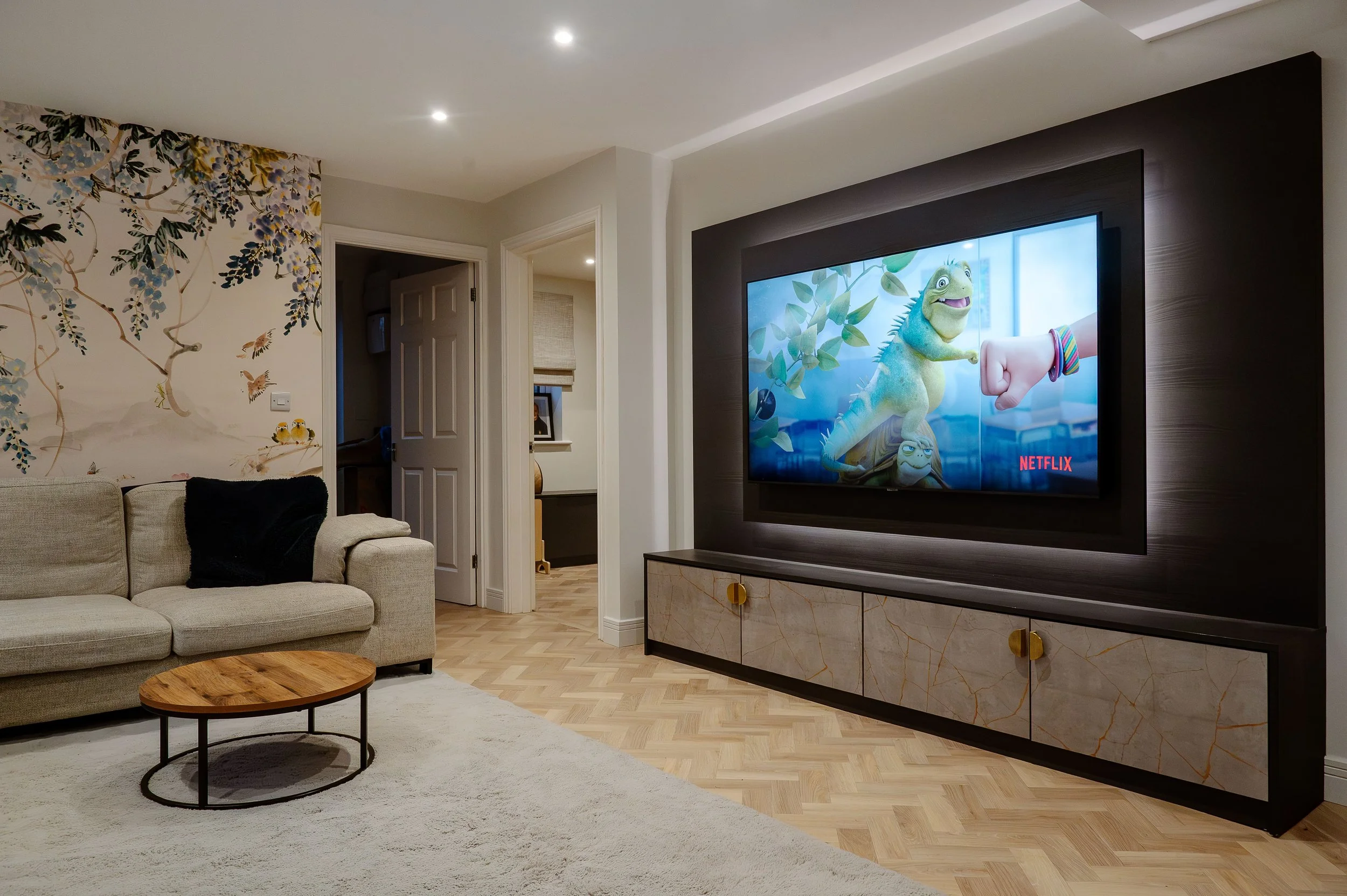 Luxurious modern media wall UK design with a large flat-screen TV, integrated linear electric fireplace, and decorative timber slat wall panels with warm ambient lighting.