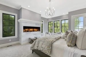 A luxury bedroom media wall installation featuring a built-in TV and a warm, atmospheric electric fire for a hotel-inspired look.